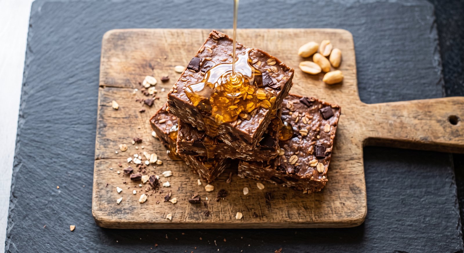A stack of thick chocolate peanut butter high protein clean bulking snack squares on a wooden board